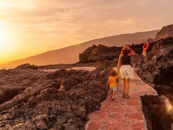 Vista de una madre e hijo disfrutando un atardecer en la playa de Tacoron en el Hierro