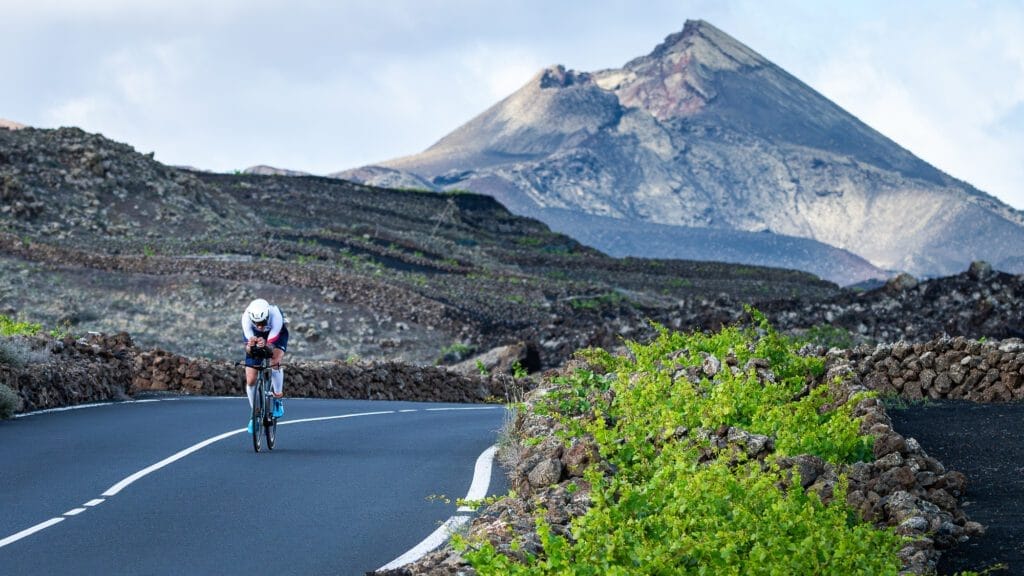 Vista de un ciclista en una carretera rodeado de piedra volcánica en una competicion
