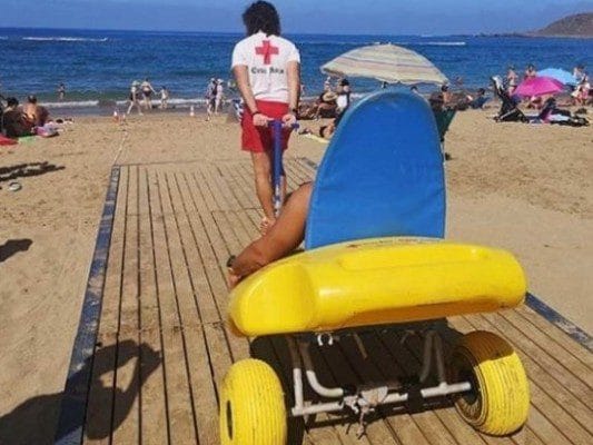 Vista de un trabajador con una persona en una silla anfibio en Las Canteras