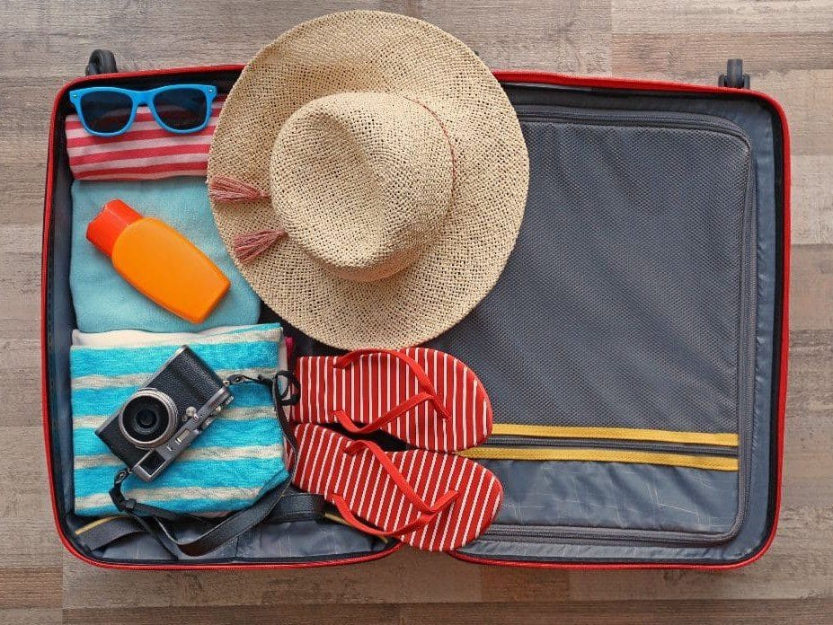 VItsa de una maleta con unas chanclas, sombrero y camara, alguno de los imprescindibles que llevar a las Islas Canarias